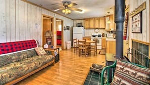A cozy living room with a sofa, a dining area with chairs, a kitchen with wooden cabinets, and a fireplace. - Secluded Remer Cabin w/ Lake Access! (Remer)