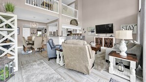 A spacious living room with a high ceiling, a dining area, and a kitchen. - Lake Conroe Waterfront | Pool + Swim/Fish Steps Away | King Suite | Patio + Amazing Views | Sleeps 6 (Montgomery)