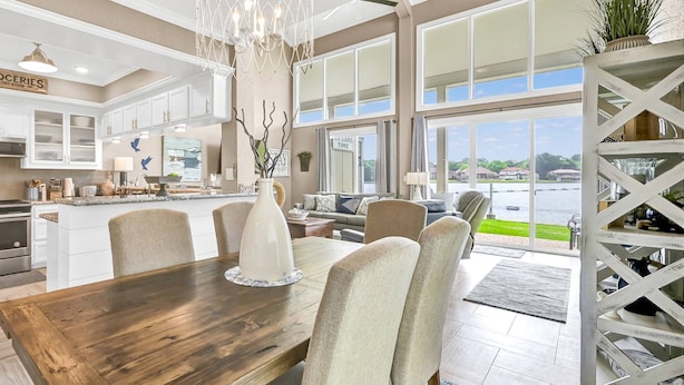 A spacious kitchen with white cabinets, a wooden dining table, and a view of a lake. - Lake Conroe Waterfront | Pool + Swim/Fish Steps Away | King Suite | Patio + Amazing Views | Sleeps 6 (Montgomery)
