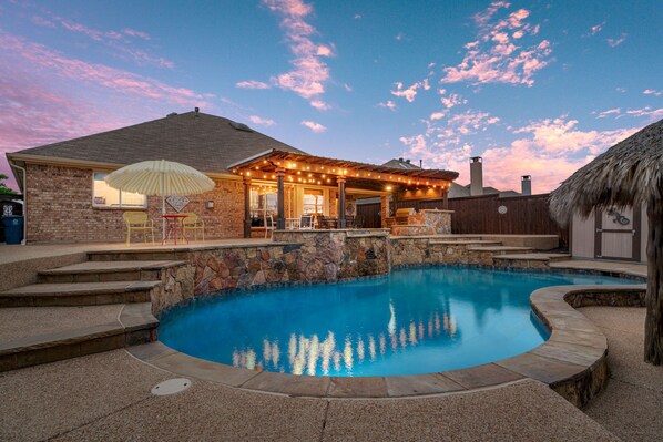 Un patio trasero con piscina, escalones de piedra y un área de patio con mobiliario exterior.