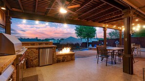 An outdoor patio with a grill, a fire pit, and a dining area with chairs and tables. - Unique heated pool & spa outdoor kitchen, game room near DFW  sleeps 10-12 (Lewisville)