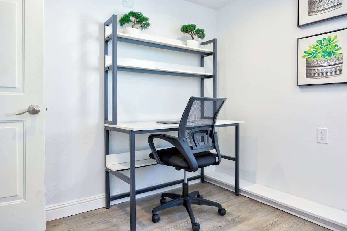 A corner office with a desk, chair, and shelving unit.
