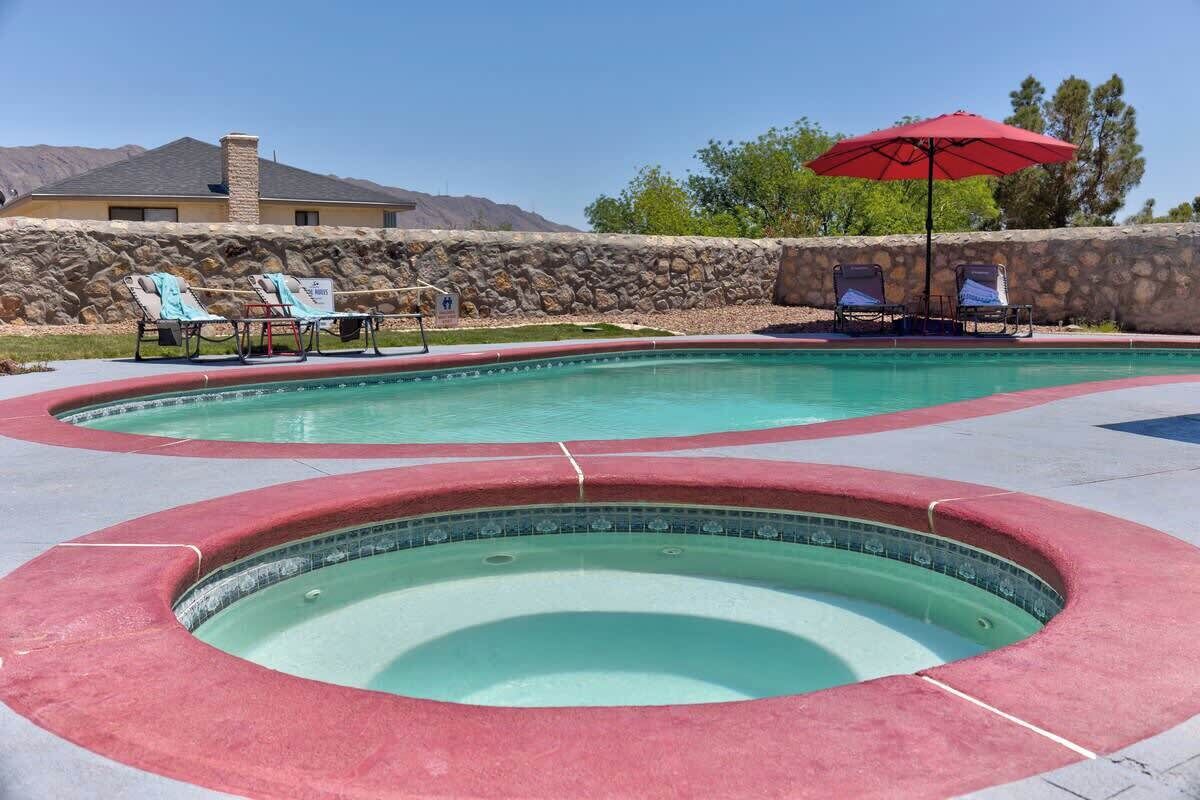 A swimming pool with a stone wall and a house in the background.