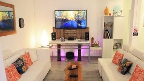 Ett vardagsrum med en TV, en soffa, ett soffbord och en bokhylla.