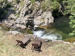 A rocky landscape with a small waterfall and two wooden benches.
