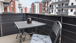 A balcony with a table and chair, a kettle, and a view of surrounding buildings. - Toia Studio (Brasov)