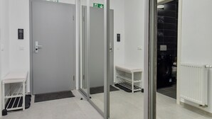 A hallway with a mirrored wall, a door, a bench, and a radiator. - Toia Studio (Brasov)