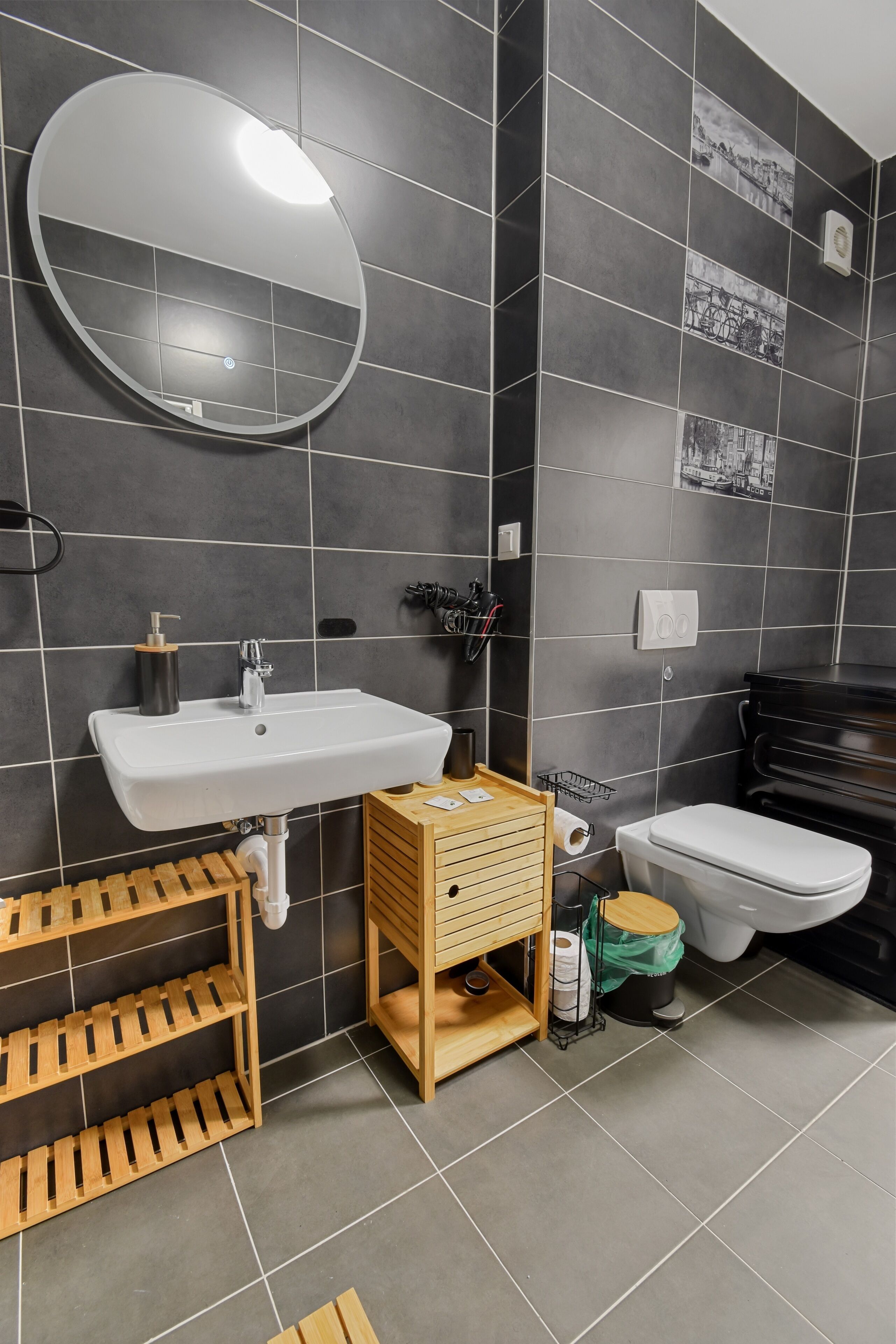 Casa de banho moderna com lavatório branco, espelho e sanita preta.
