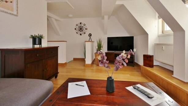 Un soggiorno moderno con un tavolino in legno, una TV e una scala che conduce a un piano superiore.
