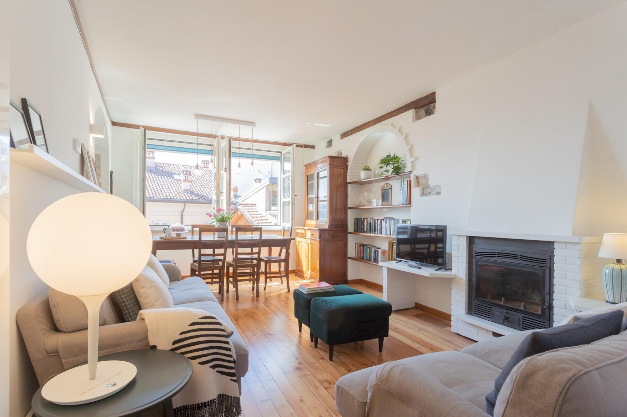 Een moderne woonkamer met een open haard, een eethoek met veel daglicht, en een gezellige zithoek.