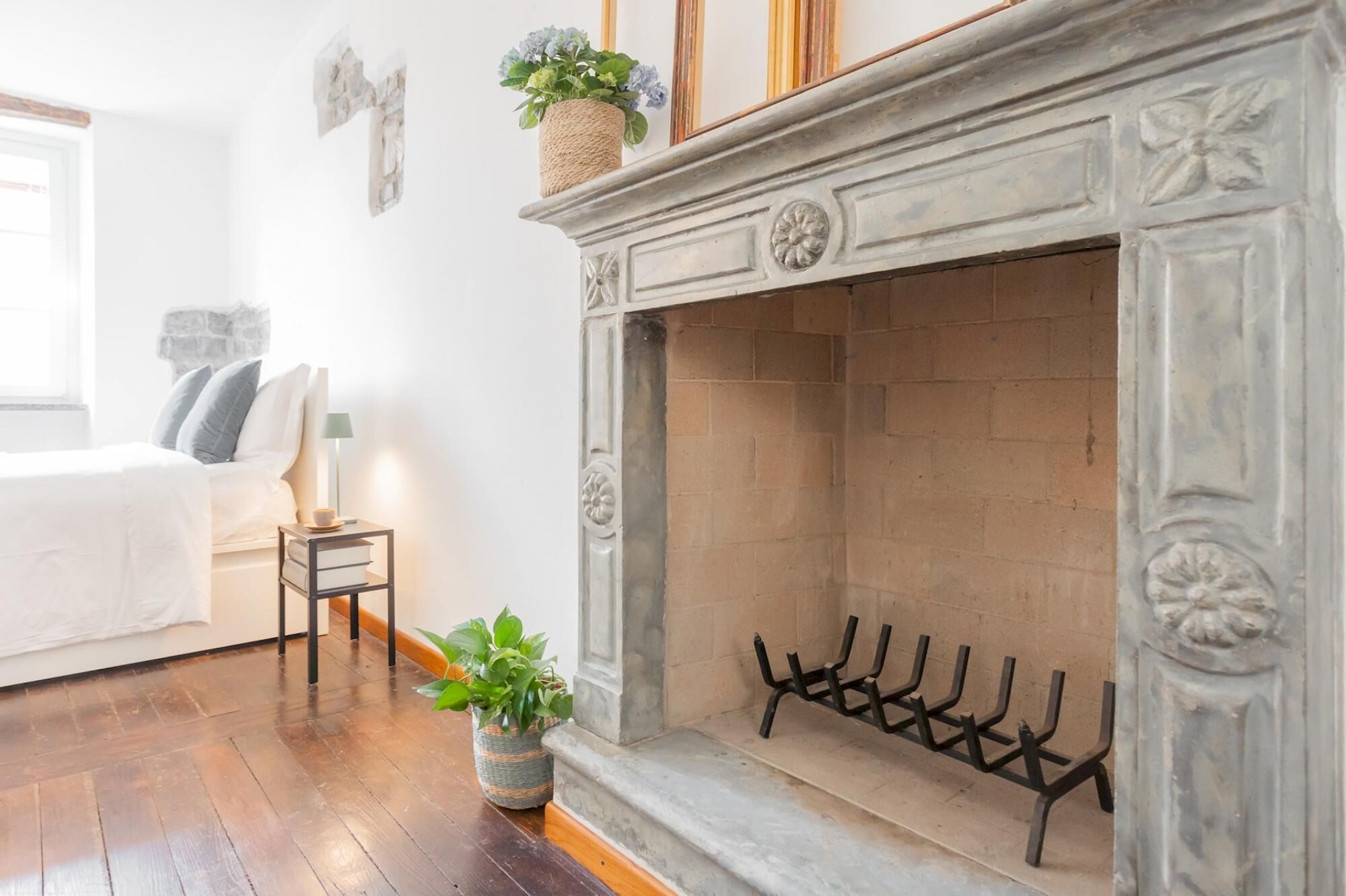 A living room with a fireplace, a sofa, a side table with books, and a plant.