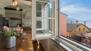Eine Küche mit einem großen Fenster, einem Esstisch mit Blumen und Blick auf Gebäude und Berge.