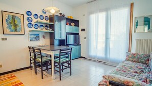 A compact living space with a dining area, kitchenette, and a sofa.