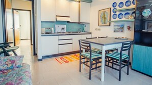 A compact kitchen with a dining table and chairs, a refrigerator, and a microwave.