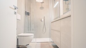 A modern bathroom with a glass-enclosed shower, a white toilet, and a built-in sink. - Il Giardino Dell Eden- Italian Homing (Sirmione)