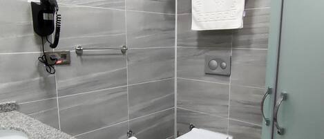 Un baño moderno con azulejos grises, un lavabo de mármol, un inodoro y una cabina de ducha con mampara de vidrio.