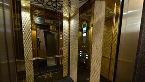 An elevator interior with reflective walls, a patterned floor, and a mirrored ceiling. - MILLS HOTEL (Tekirdag)
