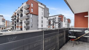 A balcony with a view of modern apartment buildings, a table with chairs, and a broom leaning against the wall. - Karina 2BDR Apartment (Brasov)
