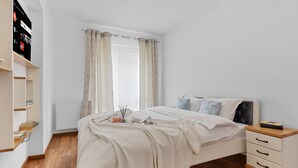 A bedroom with a bed, bedside table, and a shelf with books. - Karina 2BDR Apartment (Brasov)