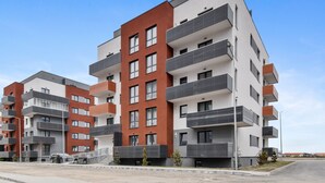 A multi-story residential building with balconies, a parking area, and a clear sky. - Karina 2BDR Apartment (Brasov)