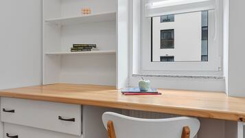 A study room with a wooden desk, white chair, and built-in shelving.