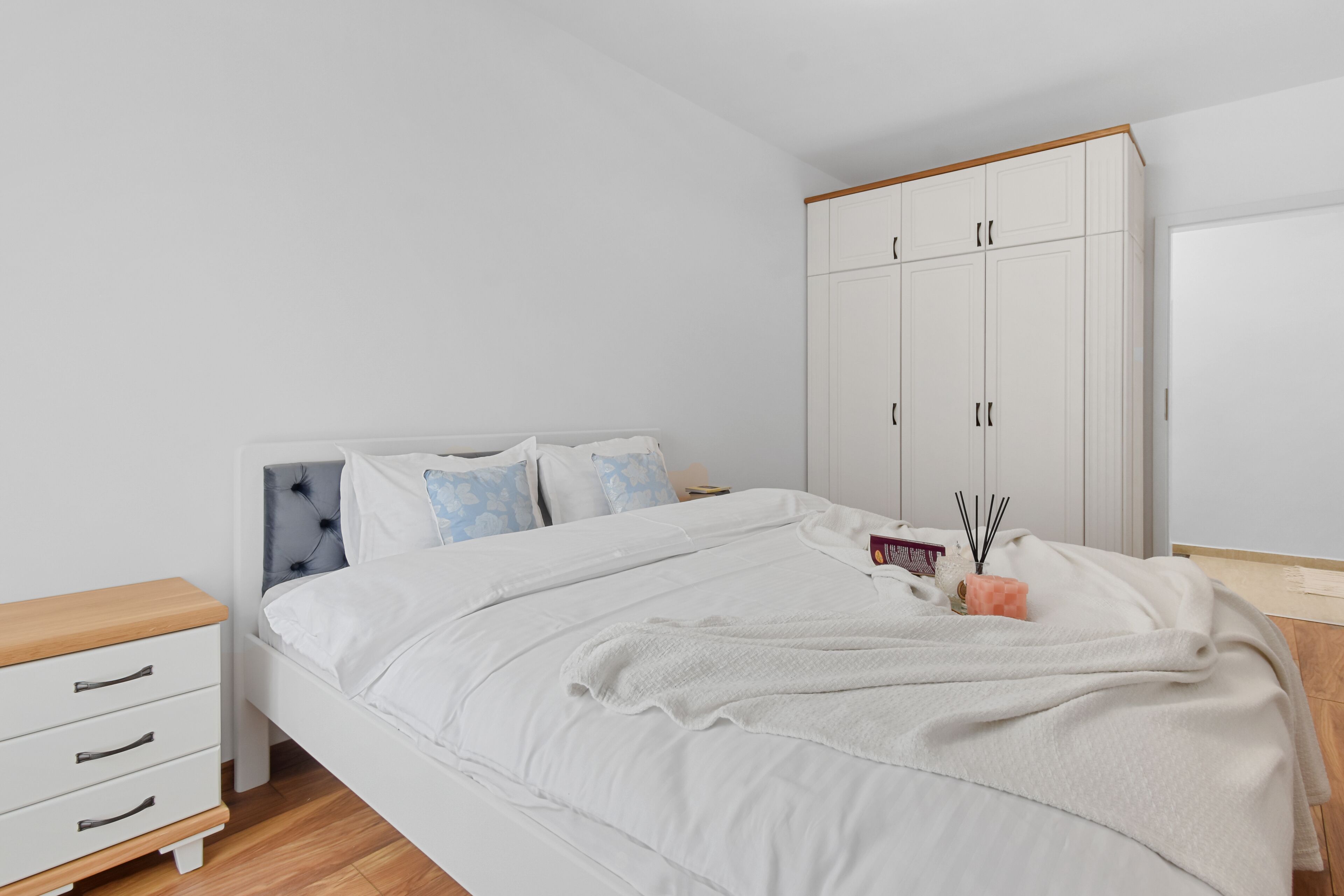 Une chambre bien rangée, avec un lit, une table de chevet, une armoire et une petite table placée à côté du lit.