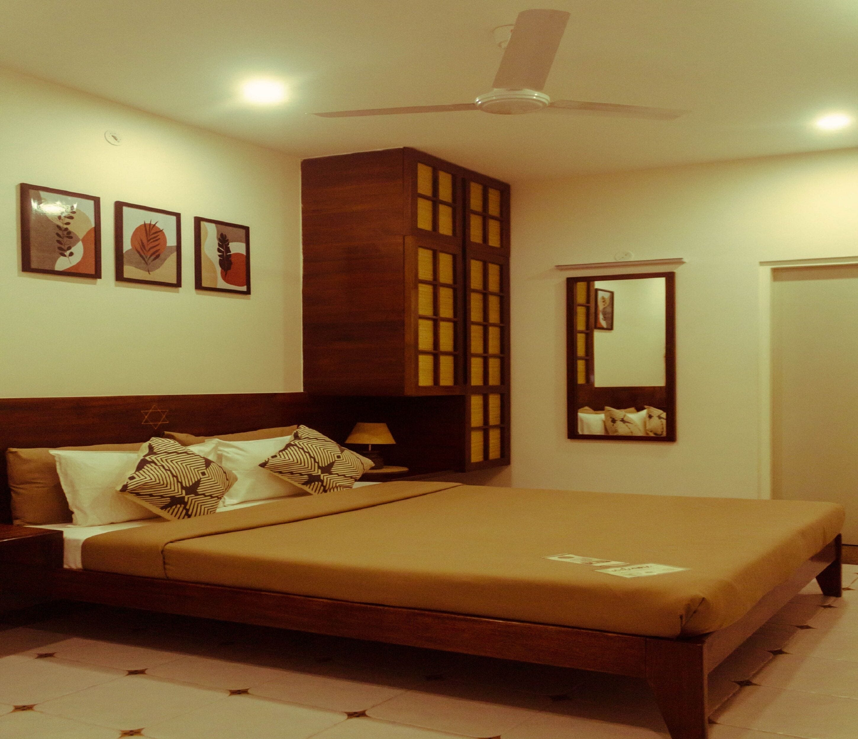 A bedroom with a bed, nightstands, a ceiling fan, and framed artwork on the walls.