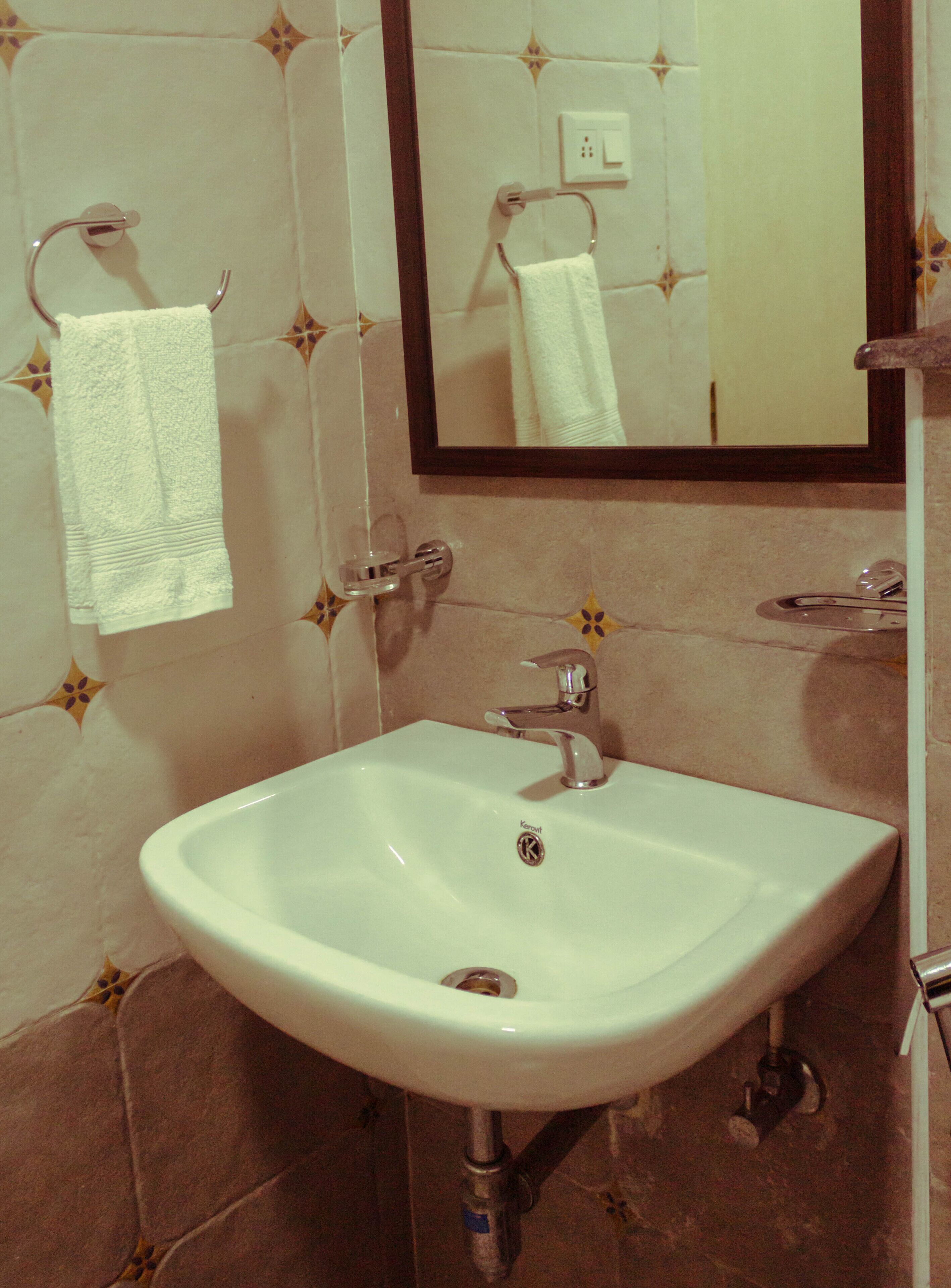 Une salle de bain avec un lavabo blanc, un miroir et une serviette suspendue à un porte-serviettes.