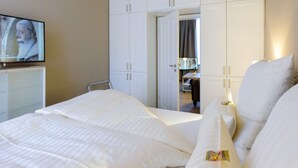 Una camera d'albergo con un letto, un comodino e una televisione appesa al muro.