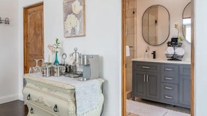 A bathroom with a grey vanity, a large mirror, and a wooden door. - Luxurious guest house with Great Views of Monterey Bay (Castroville)