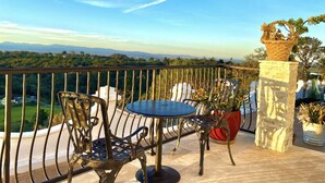 A balcony with a table and chairs, a stone pillar with a plant, and a view of the landscape. - Luxurious guest house with Great Views of Monterey Bay (Castroville)