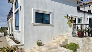 A modern house with a white exterior, a balcony with a black railing, and a stone staircase leading to the entrance. - Luxurious guest house with Great Views of Monterey Bay (Castroville)