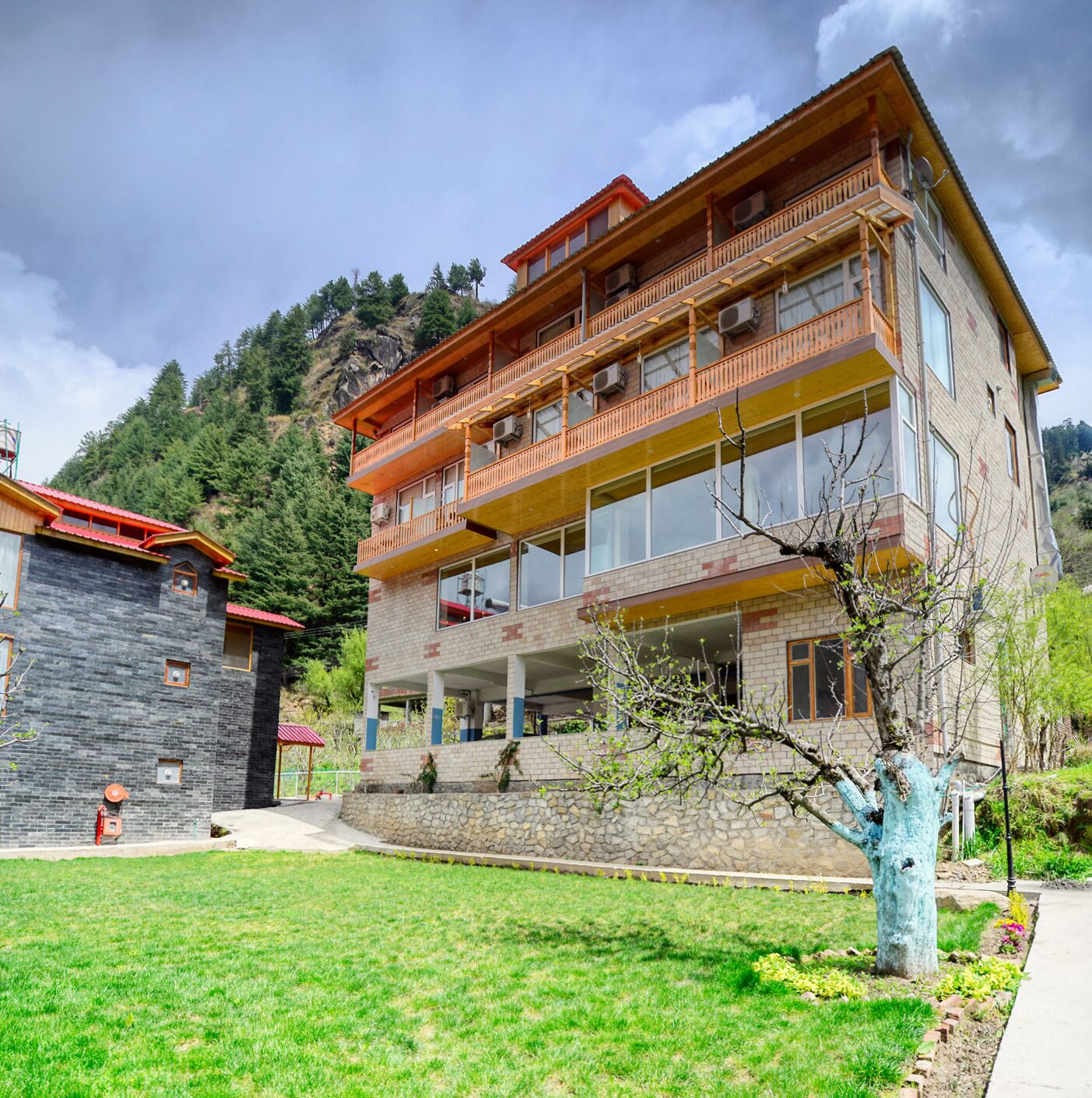 Un edificio de varios pisos con balcones, fachada de piedra y un patio cubierto de césped.