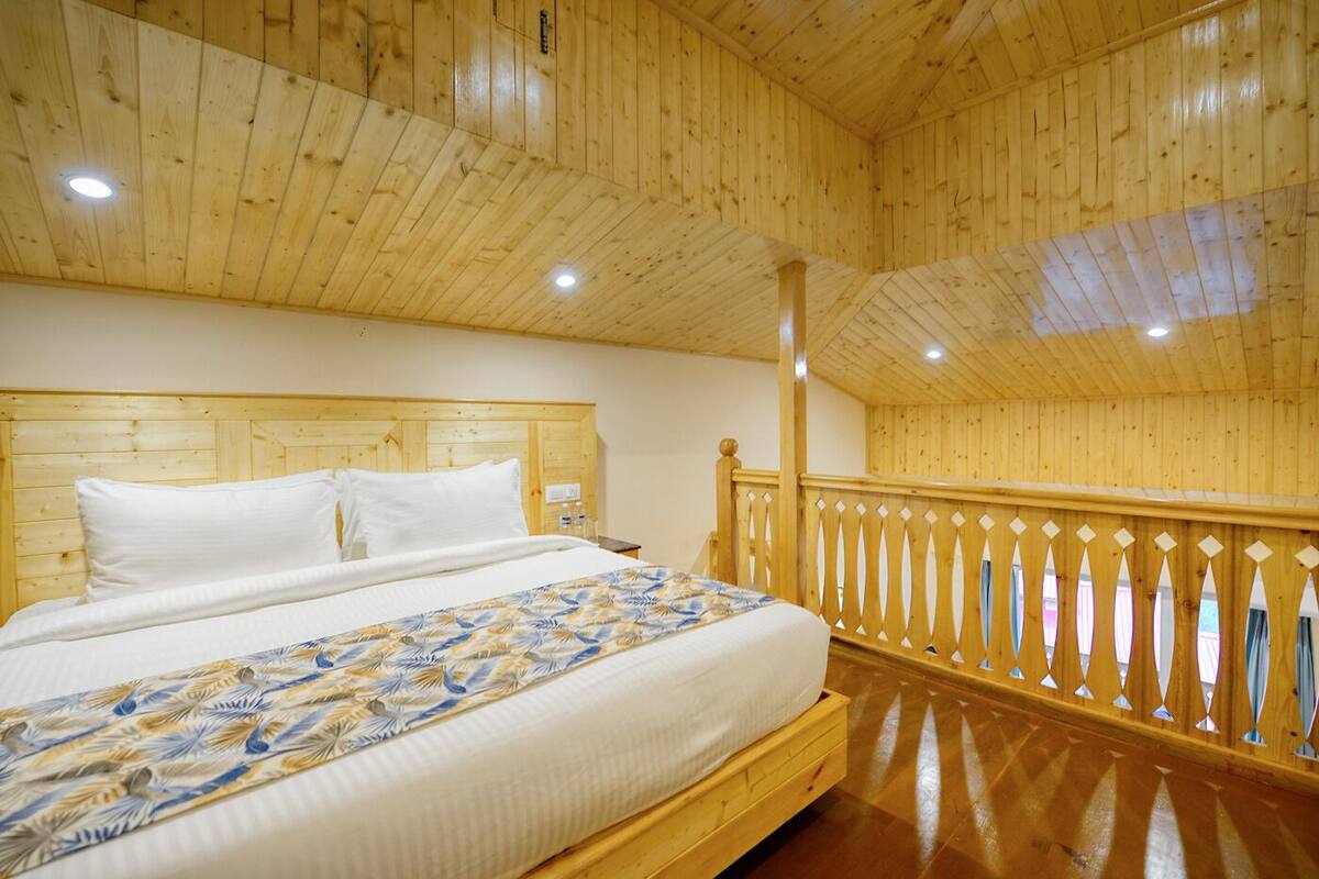A wooden-paneled room with a bed, a wooden railing, and a ceiling with recessed lighting.