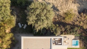An aerial view of a modern house with a large patio, a swimming pool, and surrounding greenery. - Villa Pettegola in Noto (Noto)