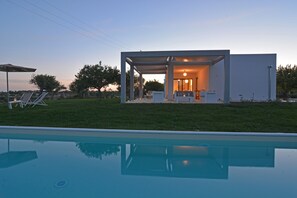 Una casa moderna con piscina, patio y vistas del paisaje circundante.