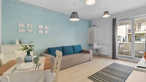 Moderni olohuone, jossa on sohva, ruokapöytä ja riippuvalaisimet.