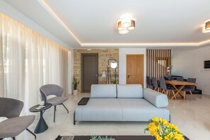 Una sala de estar moderna con sofá, sillas, una mesa de comedor y una escalera que lleva a otro nivel.