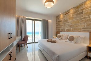Habitación de hotel moderna con una cama grande, un escritorio y una silla. Se ve el océano a través de la ventana.