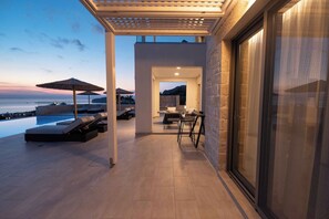 Un espacio exterior moderno con piscina, sillones de descanso y sombrillas.