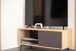A wooden TV stand with a flat-screen TV and a gaming console.