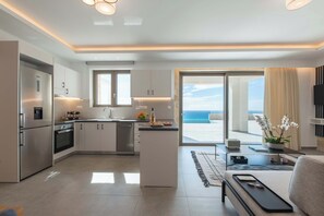 Una cocina moderna con una isla central, un área de comedor con sofá y vista al océano.