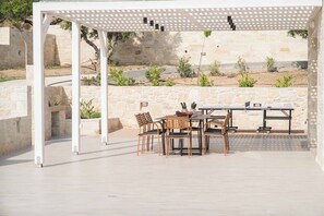En uteplats med en pergola, stenmurar och ett bord med stolar.
