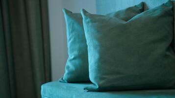 A teal sofa with two cushions against a wall.