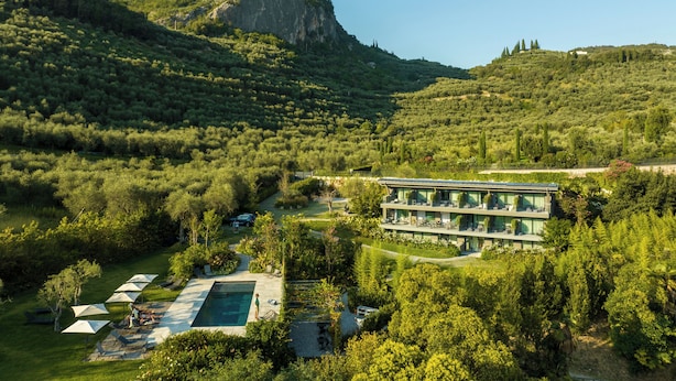 Un hôtel moderne doté d’une piscine, entouré d’une végétation luxuriante et de collines.