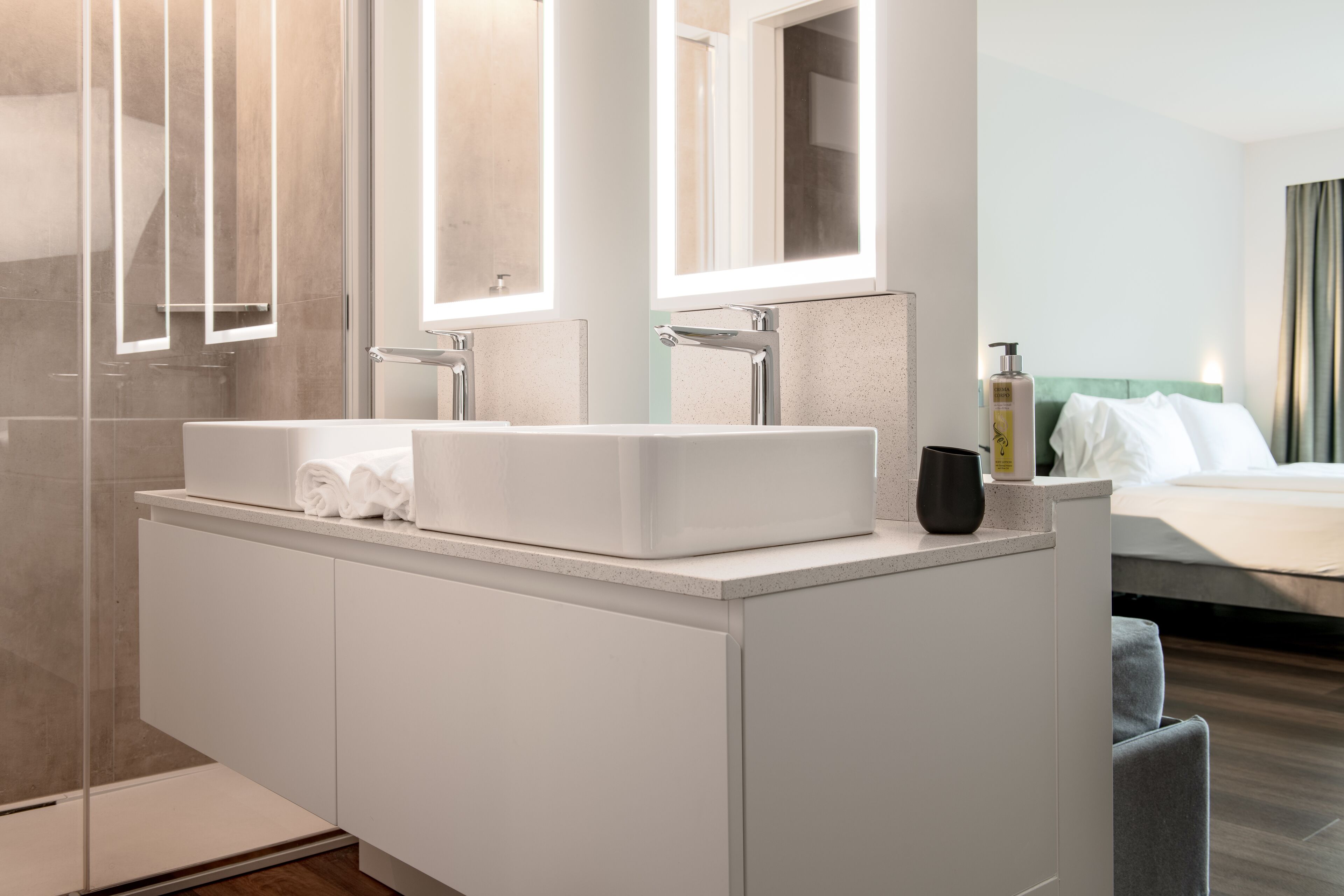 Un baño moderno con lavamanos doble, un espejo grande y cabina de ducha.