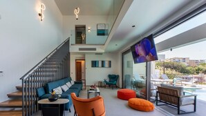A modern living room with a staircase, a sofa, a coffee table, and a TV.