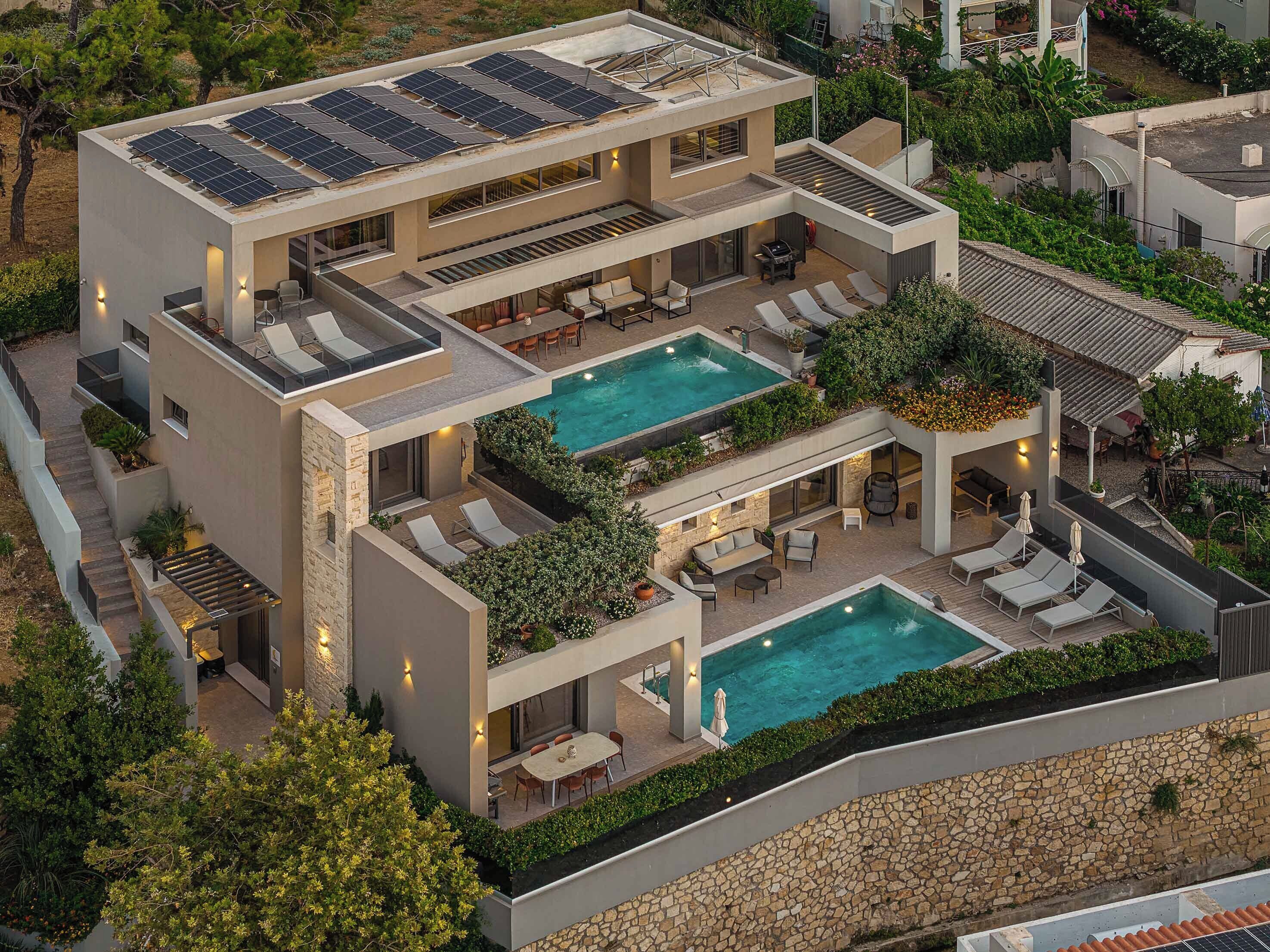 A modern multi-story house with a rooftop pool and solar panels.