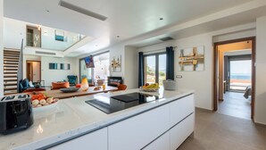 A modern kitchen with a large island, built-in appliances, and a dining area with a view.