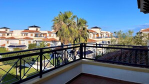 Een balkon met uitzicht op een woonwijk met huizen en palmbomen.